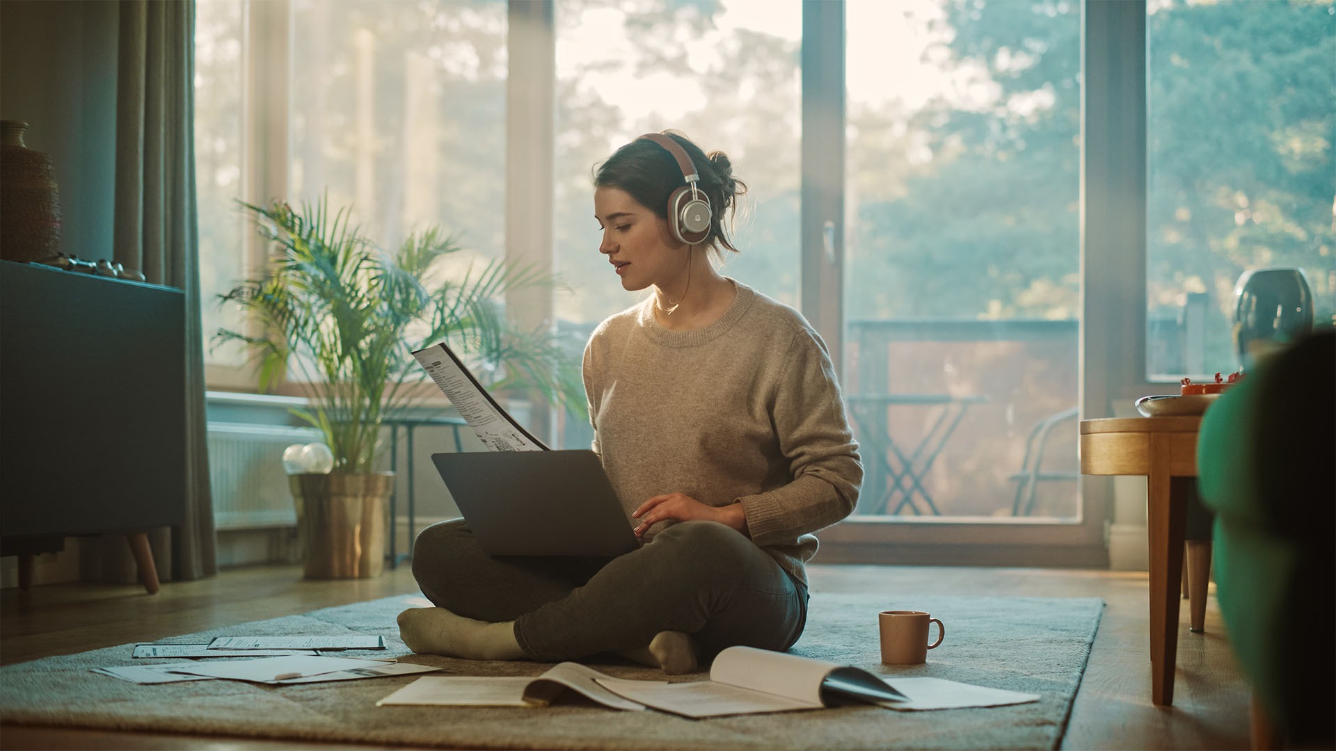 Young Woman Using Laptop at Home, Does Remote Work, Listens Music through Headphones. Beautiful Smiling Girl Sitting on the Floor Does Research on Papers, Documents, Brainstorms Creative Project, Working from home, Garden Pods, Garden Studio, Vivid Pods